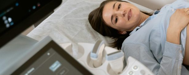 Pregnant woman undergoing an ultrasound scan, assisted by a healthcare professional in a medical clinic.